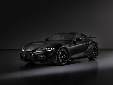 Обои на рабочий стол Toyota GR Supra A90 Final Edition 2025 черного цвета стоит в темном помещении на фоне темной стены вид три четверти спереди