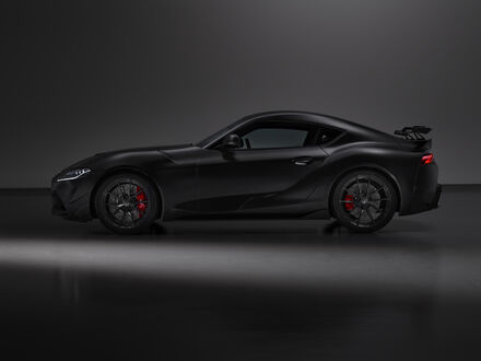 Обои на рабочий стол Toyota GR Supra A90 Final Edition 2025 черного цвета стоит в темном помещении на гладком полу вид сбоку
