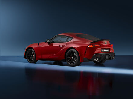 Обои на рабочий стол Toyota GR Supra Lightweight EVO 2025 красного цвета стоящая боком на сером фоне