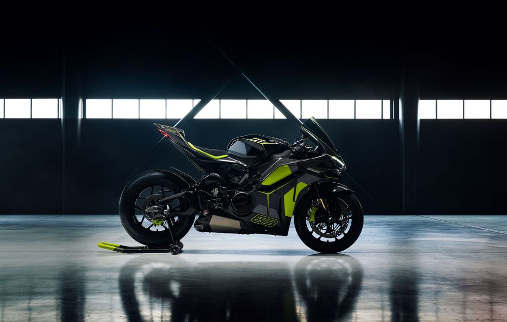 Обои для рабочего стола Мотоцикл Ducati / Дукати черного цвета с зелеными деталями стоит в ангаре на фоне больших окон при искусственном освещении