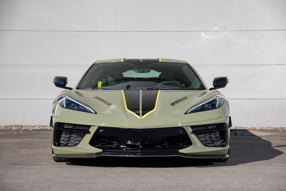 Обои для рабочего стола Chevrolet Corvette Stingray / Шевроле Корвет Стингрей оливкового цвета стоит на светлой парковке днем в солнечный день на фоне белой стены
