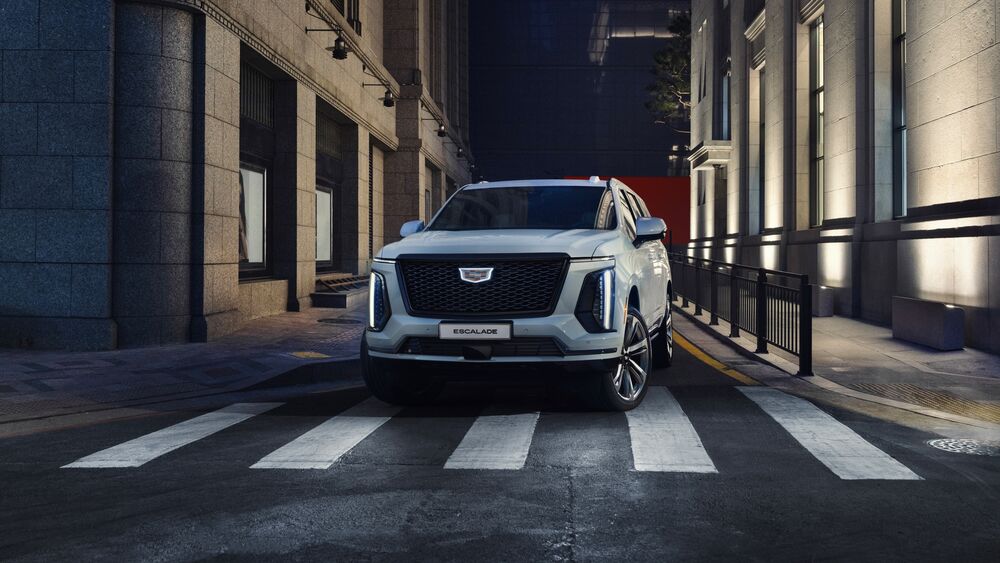 Обои для рабочего стола Автомобиль Cadillac / Кадиллак Escalade / Эскалейд белого цвета стоит на пешеходном переходе ночью в городе на фоне высоких зданий