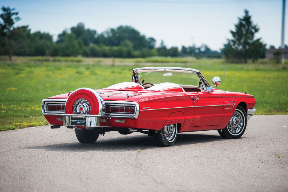 Обои для рабочего стола Красный автомобиль Ford / Форд Thunderbird стоит на зеленой лужайке в солнечный день на фоне неба вид сзади
