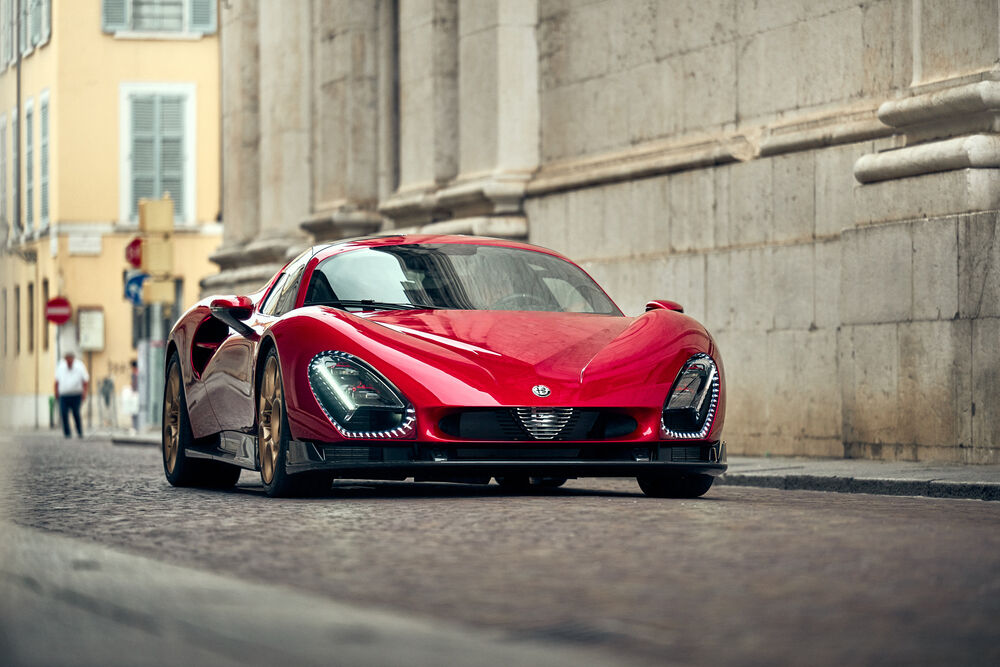 Обои для рабочего стола Красный автомобиль Alfa Romeo Stradale / Альфа Ромео Страдале на улице города днем на фоне зданий