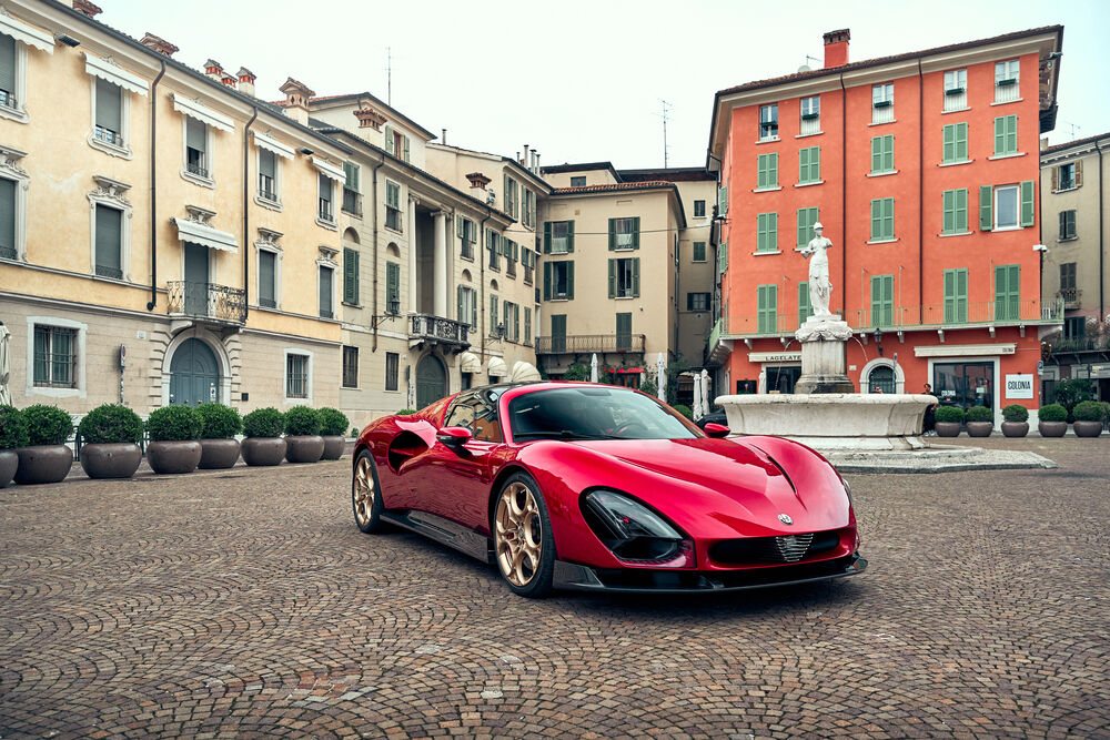 Обои для рабочего стола Alfa Romeo Stradale / Альфа Ромео Страдале красного цвета стоит на площади в Верона / Verona, Италия / Italy в пасмурную погоду на фоне старинных зданий