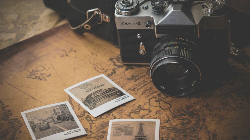 Обои для рабочего стола Фотоаппарат Зенит-Е / Zenit-E на старинной карте рядом с тремя палароидными снимками