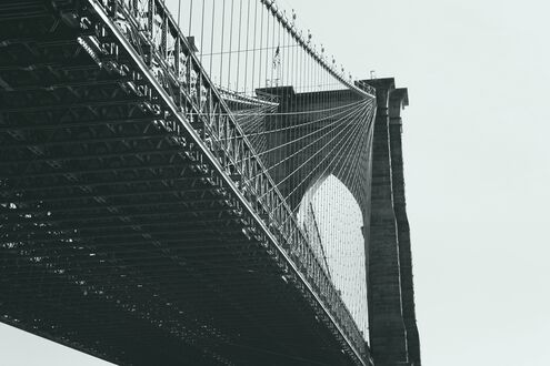 Обои на рабочий стол Бруклин / Brooklyn, США / USA, часть Бруклинского моста с подвесными тросами и каменной опорной аркой, на светлом небе
