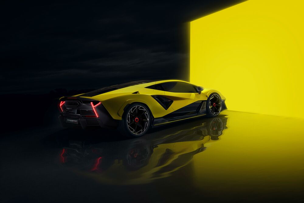 Обои для рабочего стола Желтый с черными элементами спорткар Lamborghini Fenomeno с красными фарами стоит на отражающем темном полу, на фоне светящейся желтой стены