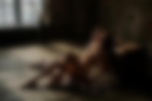 Обои для рабочего стола Обнаженная модель Polina сидит на покрывапе на полу комнаты, положив голову на сундук