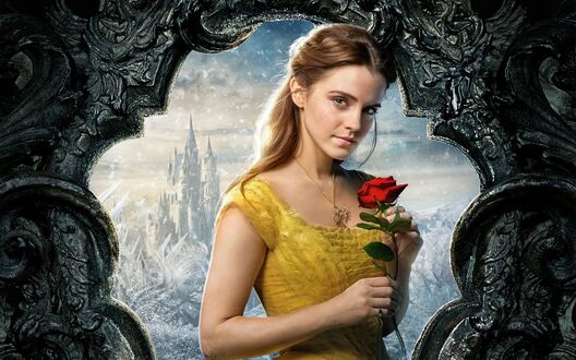 Обои на рабочий стол Эмма Уотсон / Emma Watson в роли Белль / Belle из фильма Красавица и чудовище / Beauty and the Beast в желтом платье держит красную розу, на фоне заснеженного замка и зимнего пейзажа, обрамленного темной резной аркой
