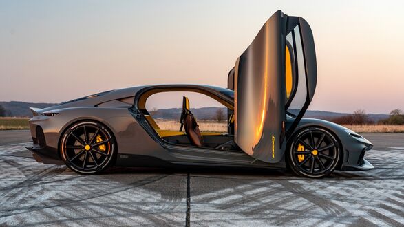 Обои на рабочий стол Серый спортивный автомобиль с открытыми дверьми и желтыми элементами интерьера на асфальтовой поверхности с шинными следами на фоне холмов, деревьев и закатного неба
