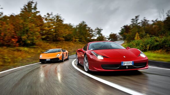 Обои на рабочий стол Красный Феррари / Ferrari и оранжевый Ламборгини / Lamborghini едут по мокрой извилистой дороге, на фоне осенних деревьев с оранжевой и зеленой листвой под пасмурным небом