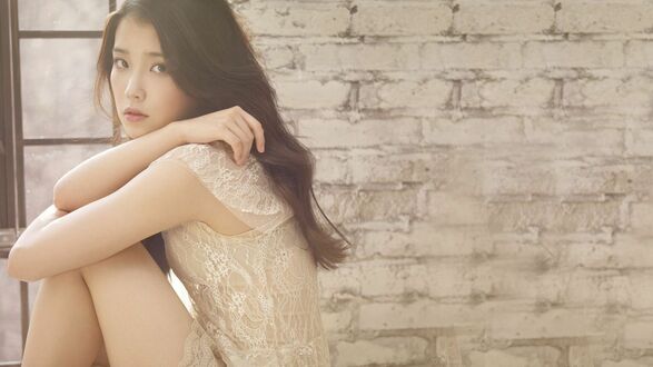 Обои на рабочий стол Певица Lee Ji-eun, IU, / Ли Джиын, АйЮ в светлом кружевном платье позирует, обхватив колени руками, на фоне кирпичной стены и оконной рамы