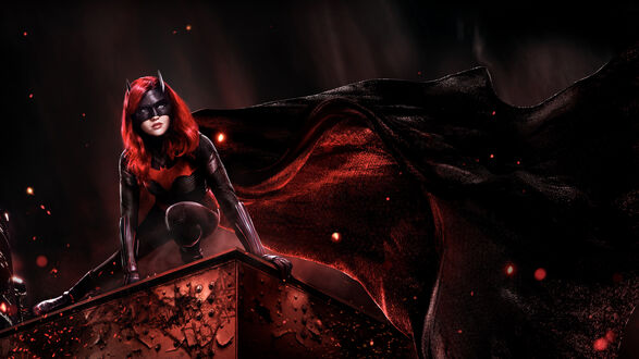 Обои на рабочий стол Девушка Бет / Beth в черном костюме Бэтвумен / Batwoman с красными элементами и маской, с красными волосами, позирует на краю здания, на фоне темного неба с красными искрами