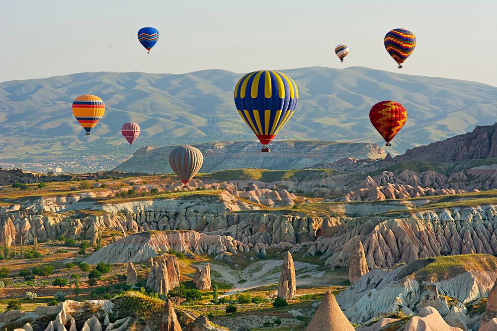 Обои для рабочего стола Каппадокия / Cappadocia, Турция / Turkey, несколько разноцветных воздушных шаров летят над скалистыми долинами и горами с высоты птичьего полета