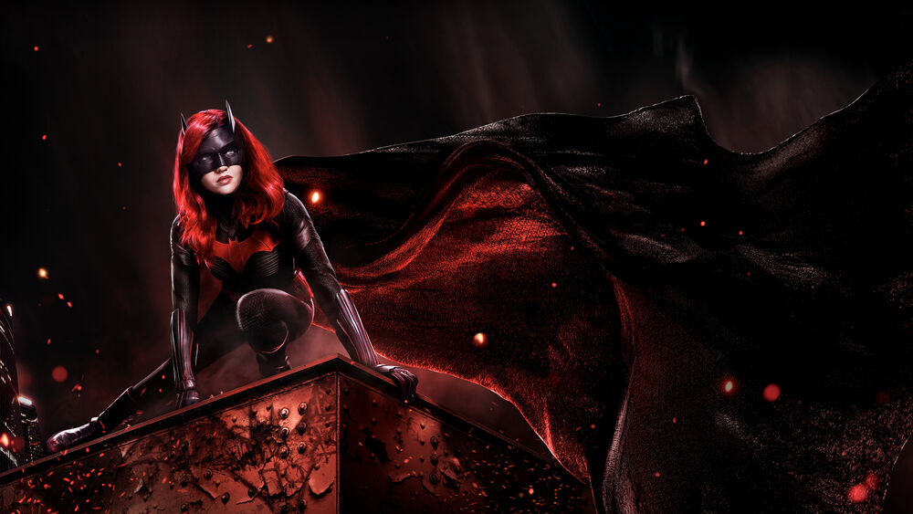 Обои для рабочего стола Девушка Бет / Beth в черном костюме Бэтвумен / Batwoman с красными элементами и маской, с красными волосами, позирует на краю здания, на фоне темного неба с красными искрами