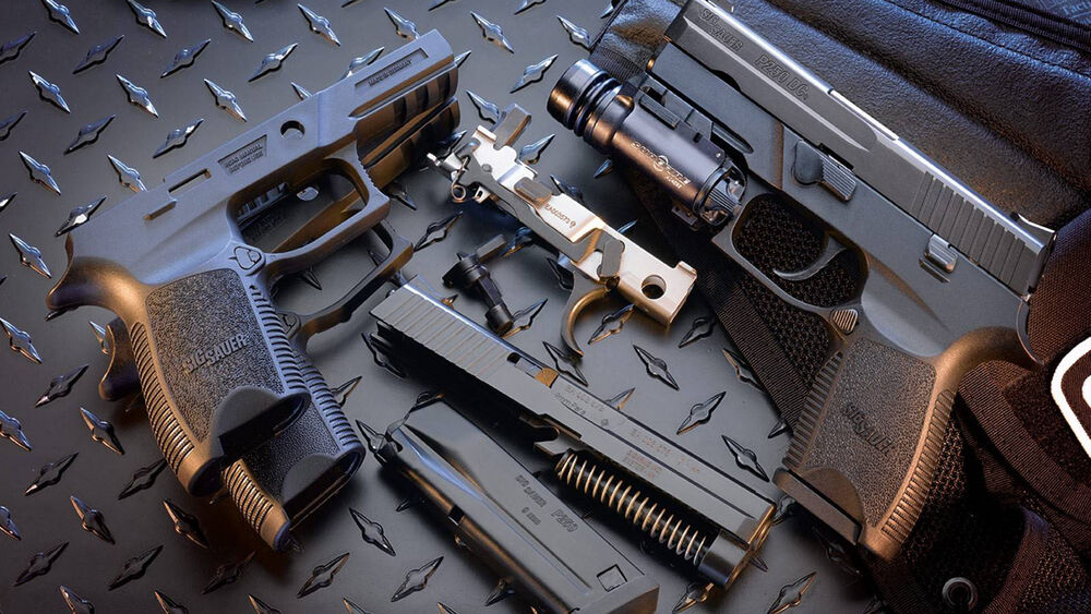 Обои для рабочего стола Пистолеты Sig Sauer P250 на темной металлической поверхности