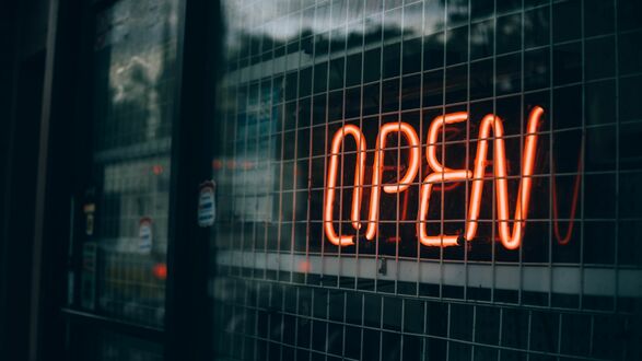 Обои на рабочий стол Красная неоновая вывеска с надписью OPEN за металлической решеткой и стеклом на фоне размытого отражения