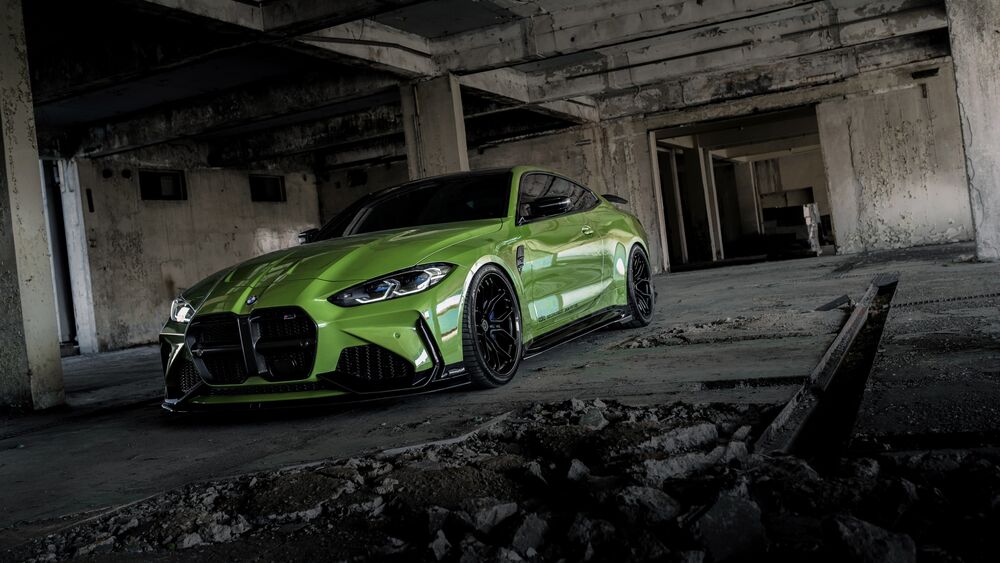 Обои для рабочего стола Зеленый спортивный автомобиль Bmw m4 с включенными фарами на фоне заброшенного бетонного здания с колоннами и строительным мусором