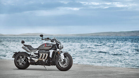 Обои на рабочий стол Мотоцикл Triumph Rocket III серого цвета стоит на подножке на сером песке на берегу водоема