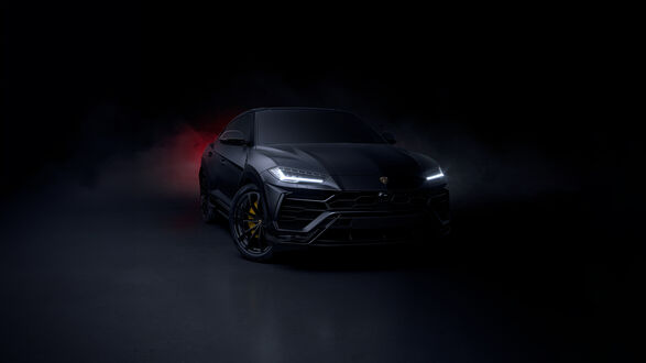 Обои на рабочий стол Черный Lamborghini Urus с включенными фарами на темном фоне