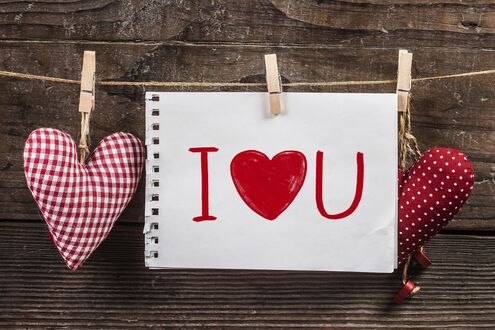 Обои на рабочий стол Белый лист бумаги с надписью (I ❤️ U) и два тканевых сердца, атрибуты Дня святого Валентина / Valentines Day, висят на веревке на фоне деревянной стены