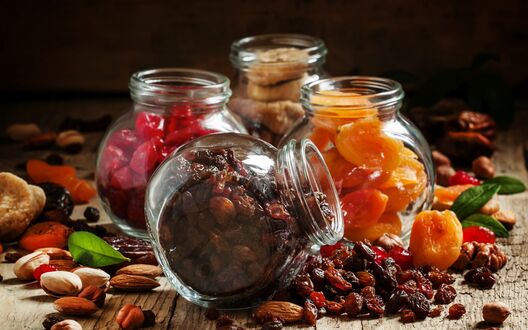 Обои на рабочий стол Четыре баночки с изюмом, курагой, инжиром и кизилом, кругом рассыпаны орехи и сухофрукты