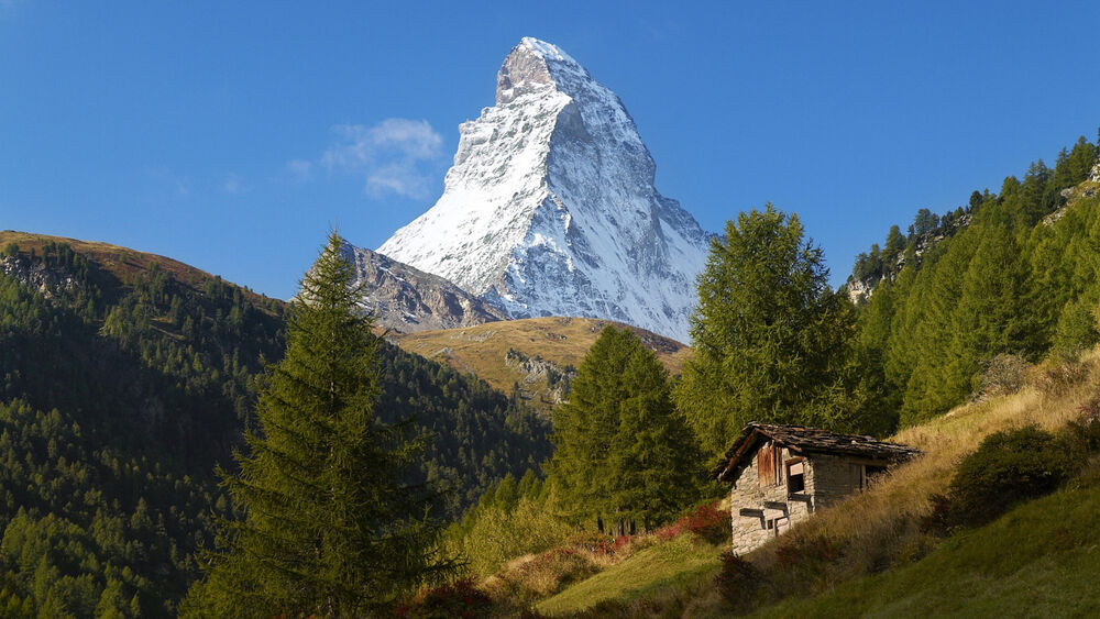 Обои для рабочего стола Гора Маттерхорн / Matterhorn, Швейцария / Switzerland, заснеженная, с хижиной и деревьями на склоне, на фоне неба