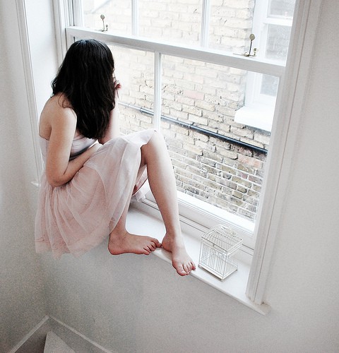 Фото Девушка сидит на подоконнике и смотрит в окно