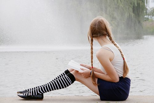 Фото Девушка читает книгу возле фонтана