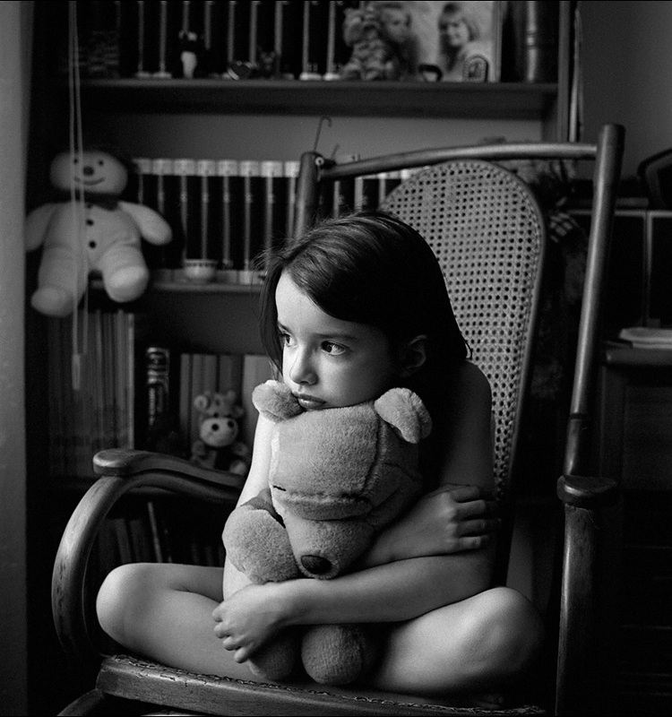 Фото Обиженная девочка с мишкой в кресле