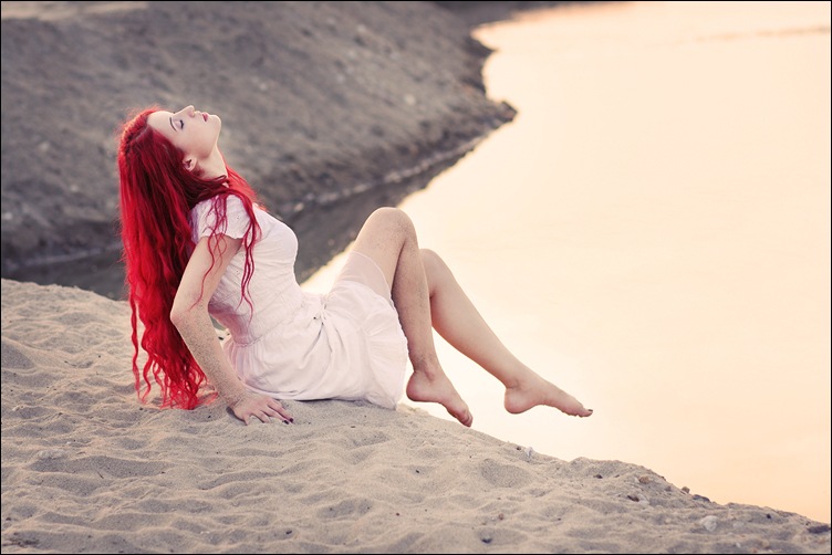 Фото Красноволосая девушка сидит на песке