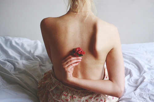 Фото Девушка держит за спиной красный цветок