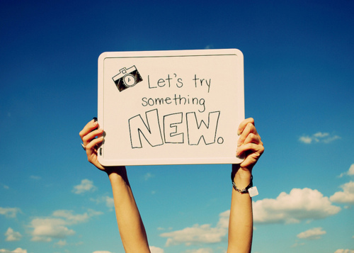 Фото Табличка с надписью 'Let's try something NEW.' / 'Попробуй что-то новое.' в руках