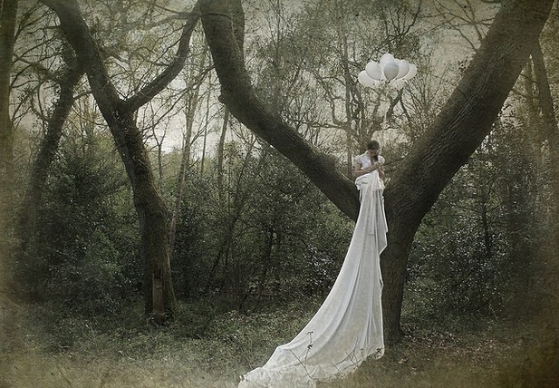 Фото Девушка в белом платье сидя на дереве держит воздушные шары