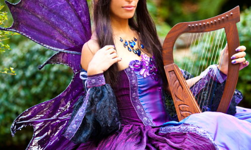 Фото Девушка в карнавальном костюме феи и с арфой в руках