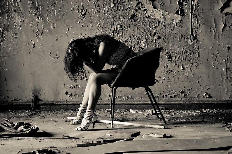 Фото Грустная девушка сидит на стуле в пустой комнате
