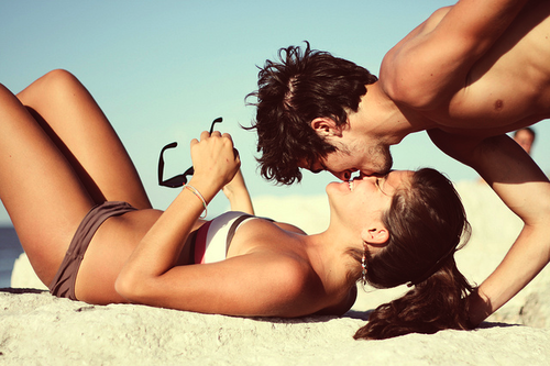 Фото Парень целует девушку, лежащую на песке