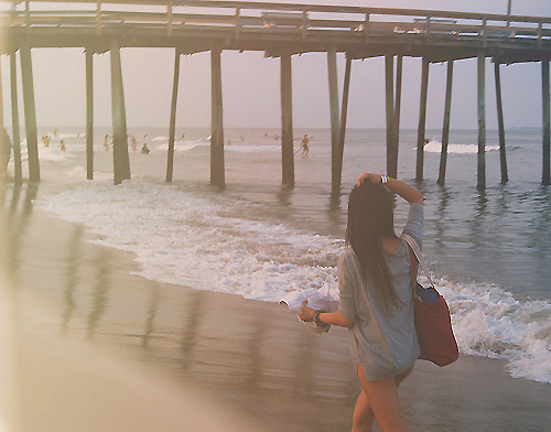 Фото Девушка гуляет по пляжу возле пирса
