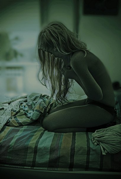 Фото Грустная девушка сидит на кровати