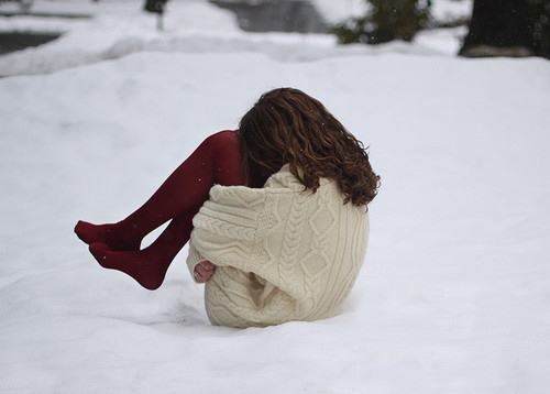 Фото Девушка сидит на снегу, обняв колени