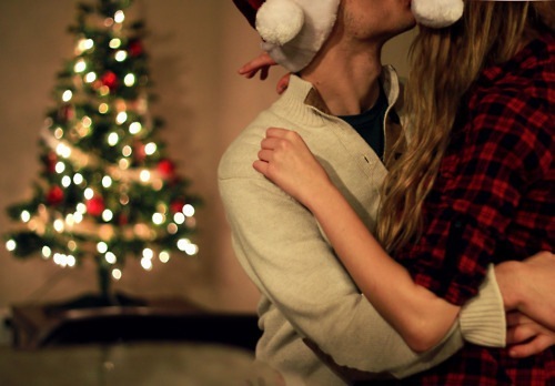 Фото Девушка с парнем в новогодних шапках целуются