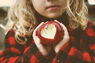 Фото Девочка держит красное яблоко с вырезанным сердцем