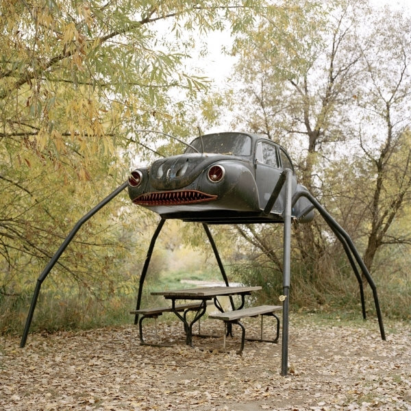 Фото Автомобиль - монстр на паучьих лапах, над столиком и скамейками, фотограф Энни Коллинж / Annie Collinge