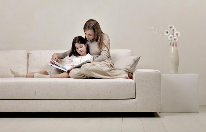Фото Мама читает дочери сказки, уютно устроившись на диване, пара фотографов Winkler Noah