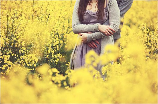 Фото Парень и девушка стоят обнявшись в поле желтых цветов