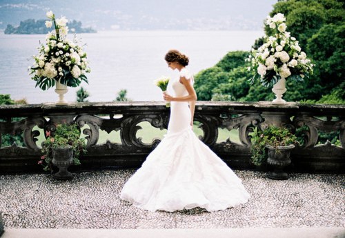 Фото Девушка одета в платье невесты и смотрит на букет цветов