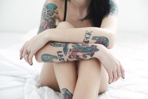 Фото Девушка с татуировками на руках сидит на кровати