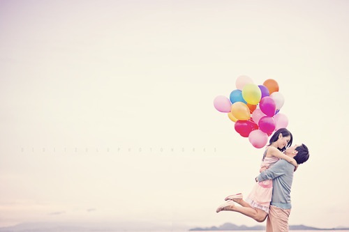 Фото Парень держит на руках девушку, которая держит связку воздушных шаров