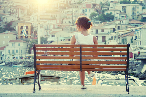Фото Девушка сидит на скамье на набережной и смотрит на город